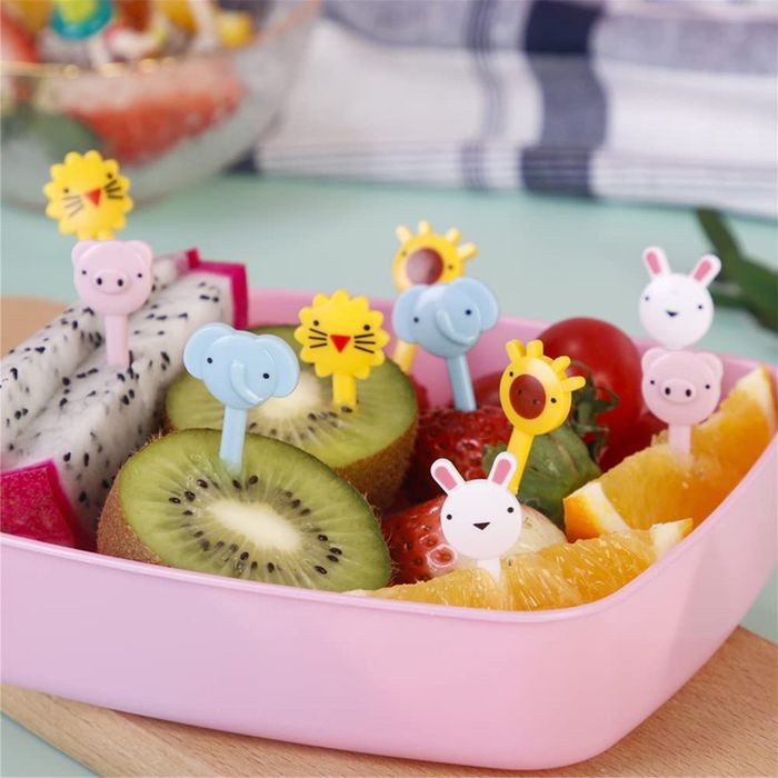 A fruit salad served in a pink container, adorned with animal-shaped food picks featuring bunnies, lions, and elephants. A creative and healthy snack idea for children