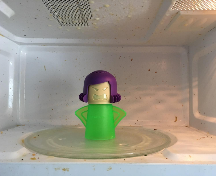 Reviewer’s before photo of the green Angry Mama in a dirty microwave