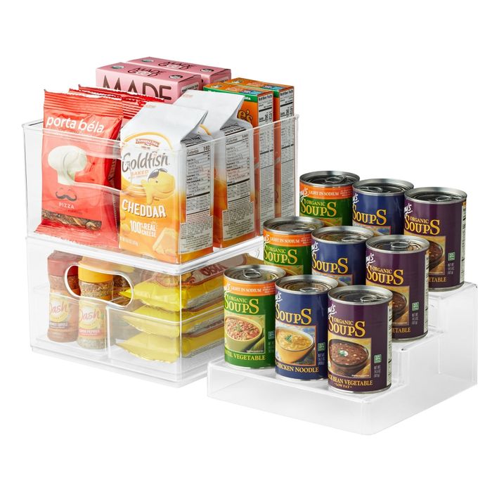 Transparent acrylic organizers showcasing an assortment of snacks, canned soups, and boxed foods neatly arranged.