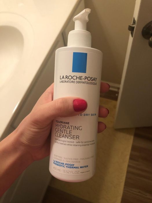 A reviewer holding the bottle of the cleanser
