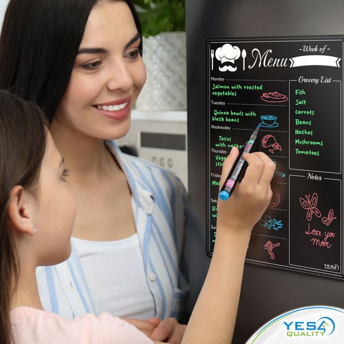Two women are seen using a magnetic meal planning board on a refrigerator, detailing meals such as salmon and tacos, along with a grocery list and notes section.