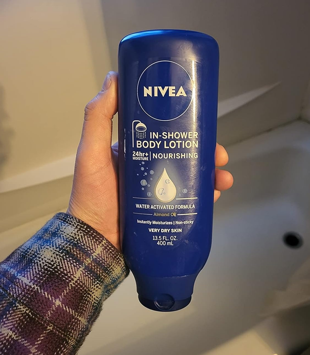 The reviewer displaying the bottle of in-shower lotion