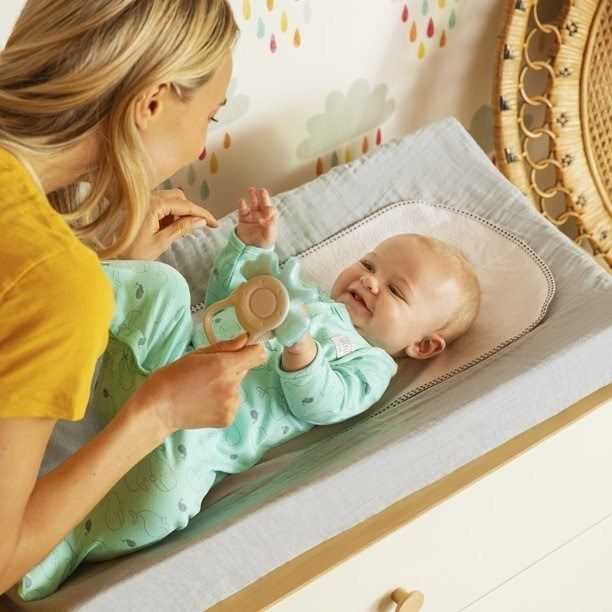 A parent enjoys playing with their baby on the changing table.