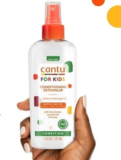 Hands showcasing the Cantu Kids Conditioning Detangler bottle set against a clean white backdrop with orange details.