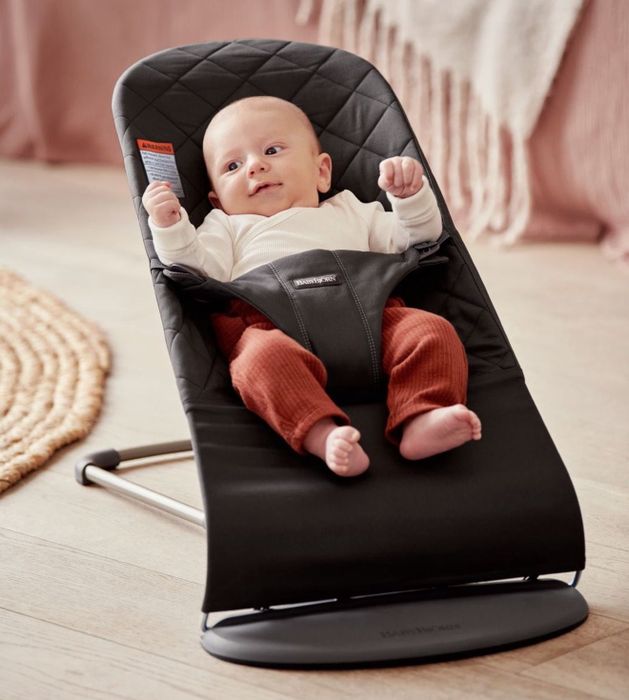 A baby sitting in the Baby Bjorn bouncer.