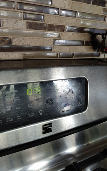 The top of the oven with a screen and timer covered in greasy fingerprints