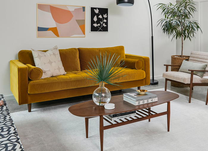 A lifestyle image featuring a walnut wood oval storage coffee table in a cozy living room setting.