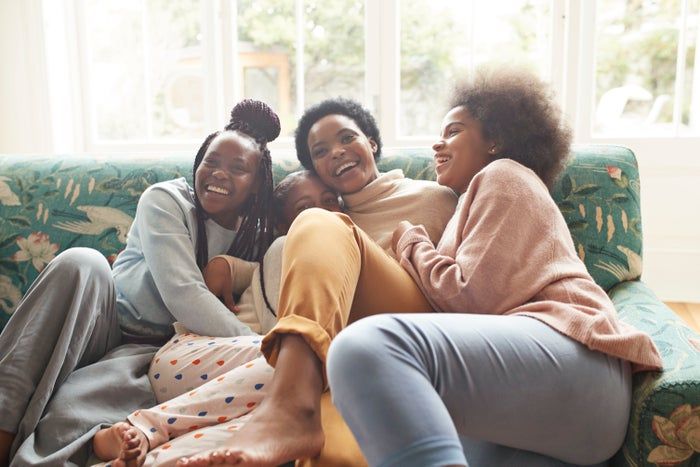 A group of four friends enjoying each other’s company and laughing together on a cozy couch in a living room