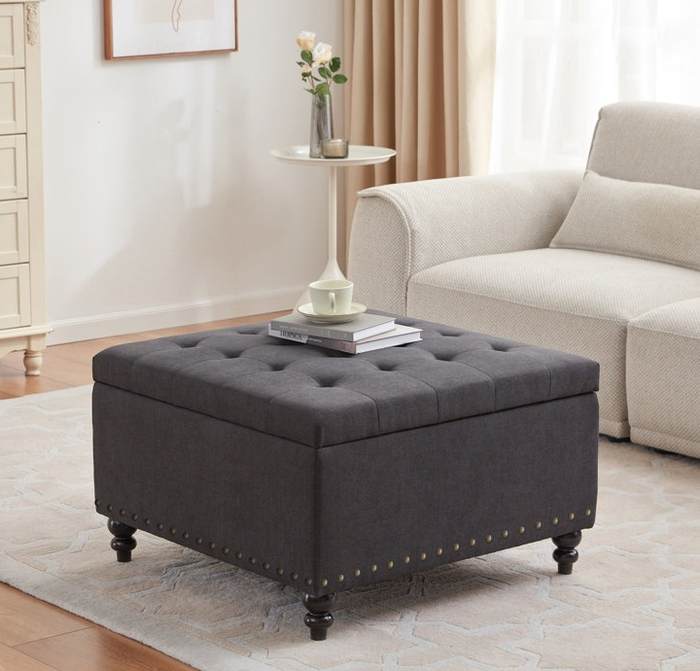 A tufted ottoman in a stylish charcoal gray shade.