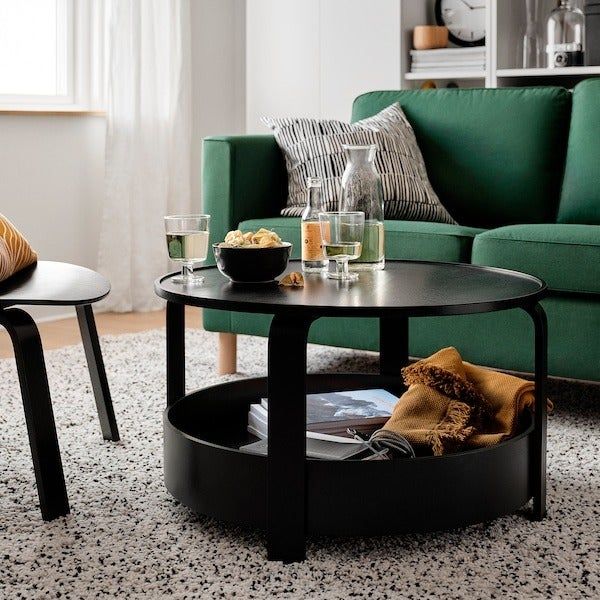 The same table in black, with a blanket and magazines resting in the bottom tray.