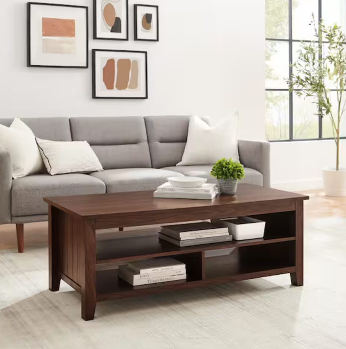 A modern living room featuring a gray sofa, abstract wall art, a dark wood coffee table, and large windows letting in plenty of natural light.