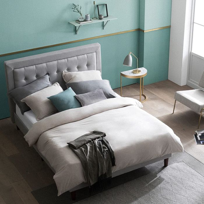 A bed with a gray, tufted upholstered bed frame