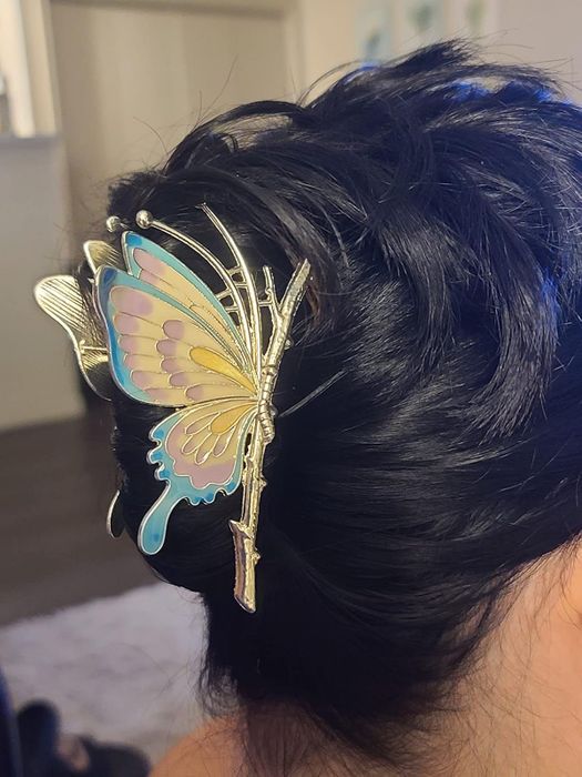 A hair styled with a delicate metal butterfly hairpin, its wings intricately detailed. The ideal addition to bring grace to any outfit.