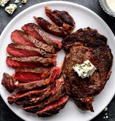 Sliced and whole cooked steak served with a pat of herb butter on top, perfect for food shopping articles