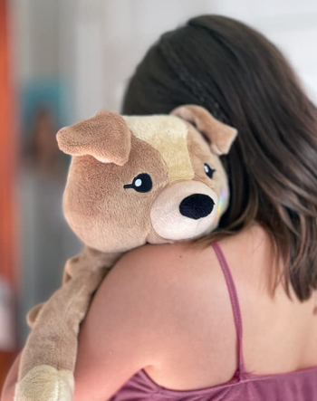 Model holding a medium-sized brown dog plush