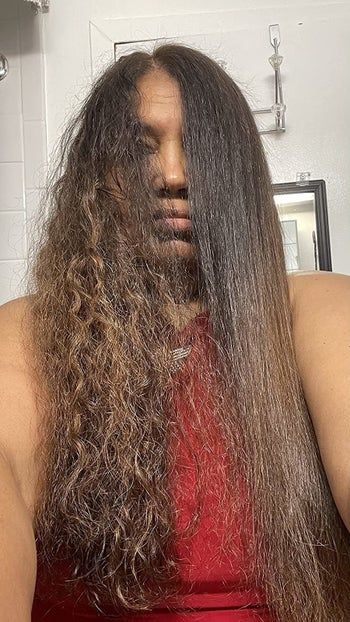 Reviewer showing one side of their hair curly and the other side sleek and straight, thanks to the anti-frizz treatment