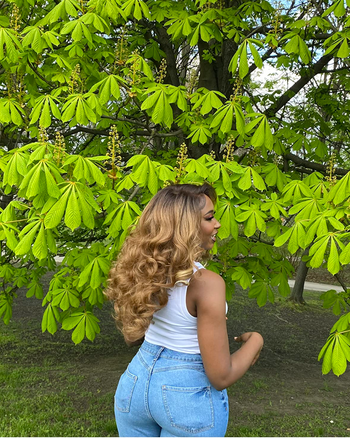 A reviewer showing off the back of a honey blonde wig.