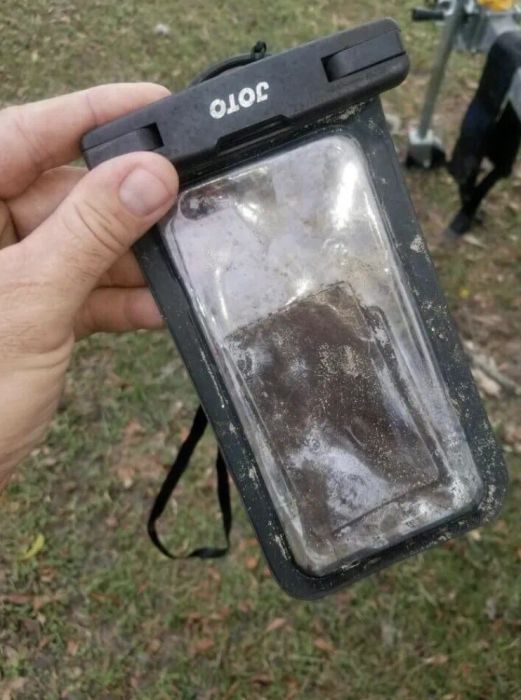 A reviewer shows their phone inside the pouch, covered in water and mud.