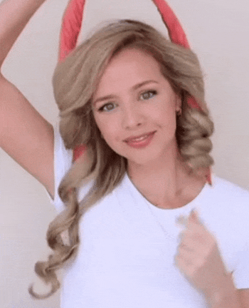 A model gently pulling large curls from their hair, then shaping them into smaller, tighter curls.