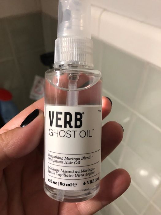 A reviewer holding a bottle of Verb Ghost Oil in their hand.