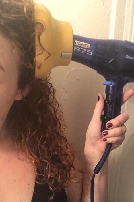 Reviewer using the diffuser attachment to blow dry their curly hair