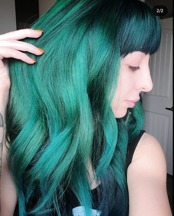 A reviewer displaying her hair styled in a green ombre gradient.