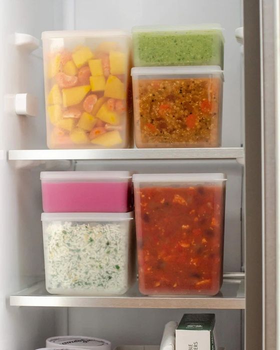 Various food items neatly organized in clear plastic containers inside a fridge, as seen in an article about product storage and organization