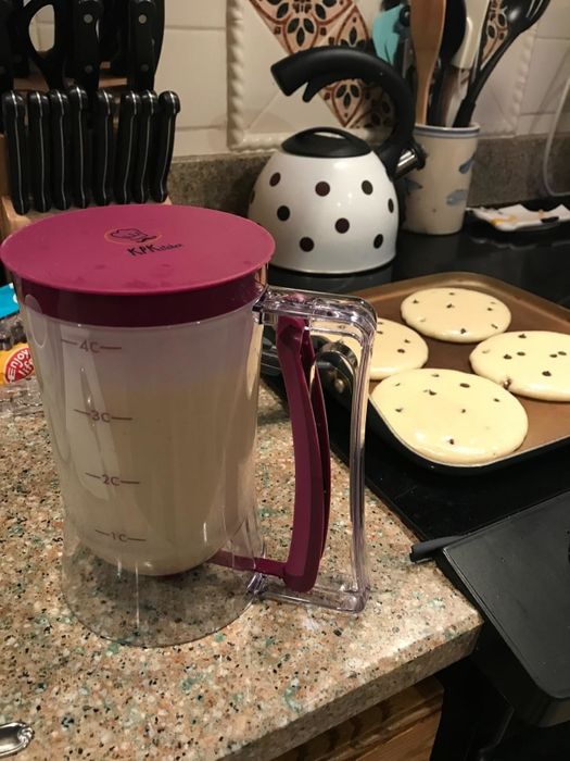 A reviewer photo featuring their pancake batter dispenser on the counter, with perfectly poured round pancakes cooking on the stove in the background