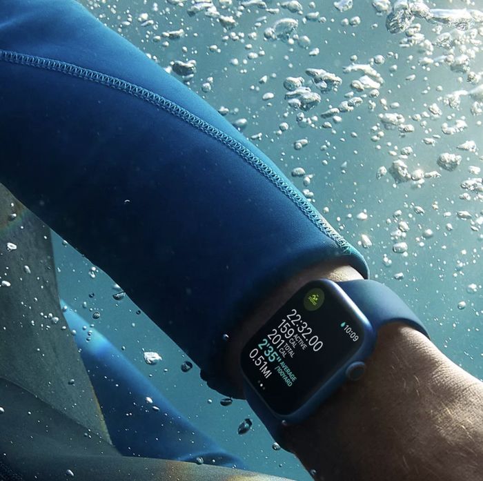 A model wearing an Apple Watch with a blue strap while swimming in the water