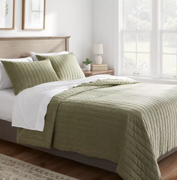 A green quilt draped elegantly over a bed.