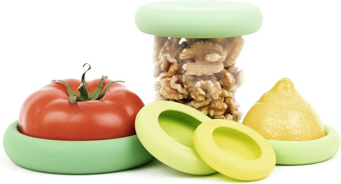 Reusable silicone food savers in action, with a tomato, walnuts, and lemon inside