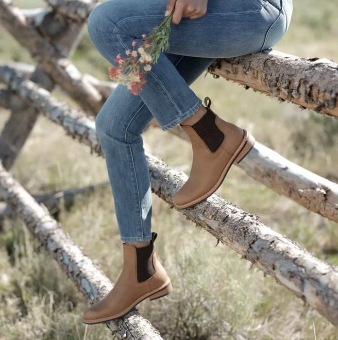 A model perched on a tree fence, sporting light brown ankle tab boots