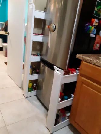 A reviewer’s photo showing the rolling cart tucked between the fridge and kitchen cabinet.