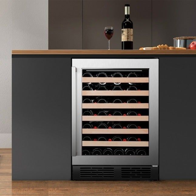 A contemporary kitchen showcasing a built-in wine cooler stocked with wine bottles, a wooden counter with a glass and bottle of wine, and a pot holding utensils beside it