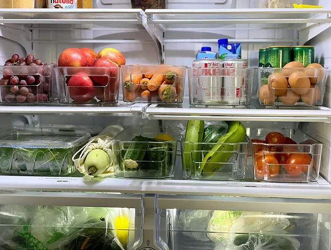 A review image showing clear plastic bins with handles, filled with fruit inside a fridge