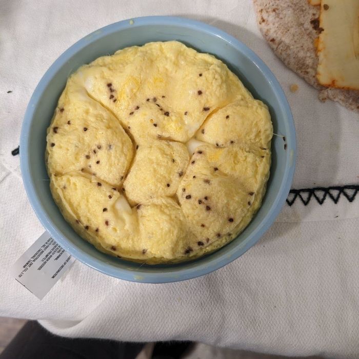 A blue bowl filled with a fluffy, yellow dish, likely seasoned with herbs. A piece of flatbread is visible in the background