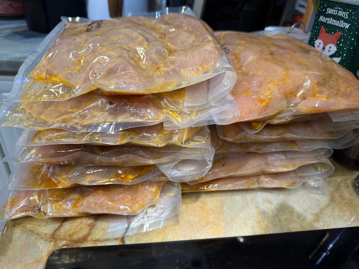 Several vacuum-sealed packages of marinated chicken breasts neatly stacked on a countertop