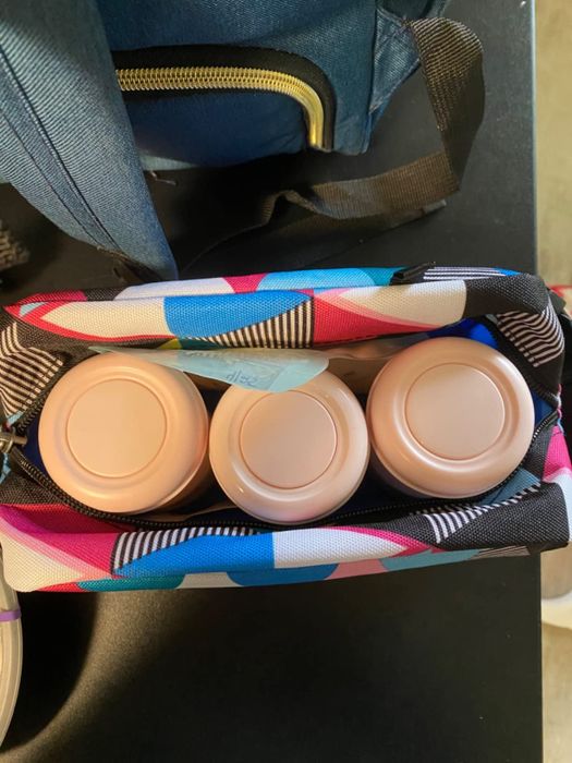 An open diaper bag with three beige containers neatly packed inside a colorful striped pouch