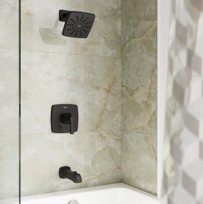 A contemporary bathroom featuring marble tiles, with a square showerhead, wall-mounted controls, and faucet in a sleek matte black finish.