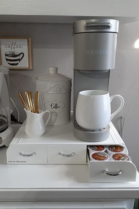 A reviewer displays a white organizer with their Keurig placed on top, showcasing the functional setup.