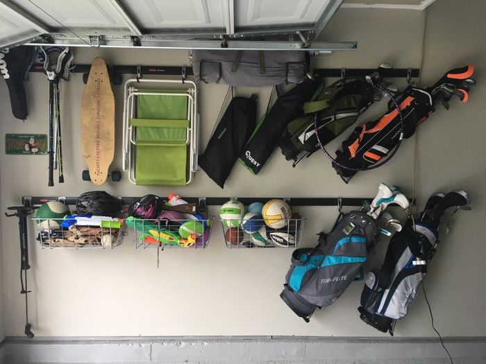 A reviewer shows a photo of their garage perfectly organized, with everything neatly hanging on track rails—beach chairs, golf clubs, kids' toys, and more.