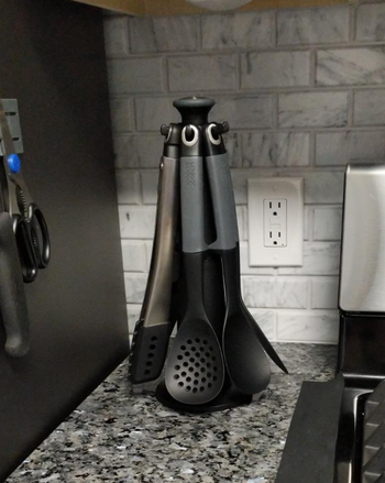 A set of kitchen utensils standing upright in a holder on a countertop.