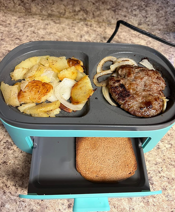 A 3-in-1 cooker preparing hash browns, meat, and toast at the same time.