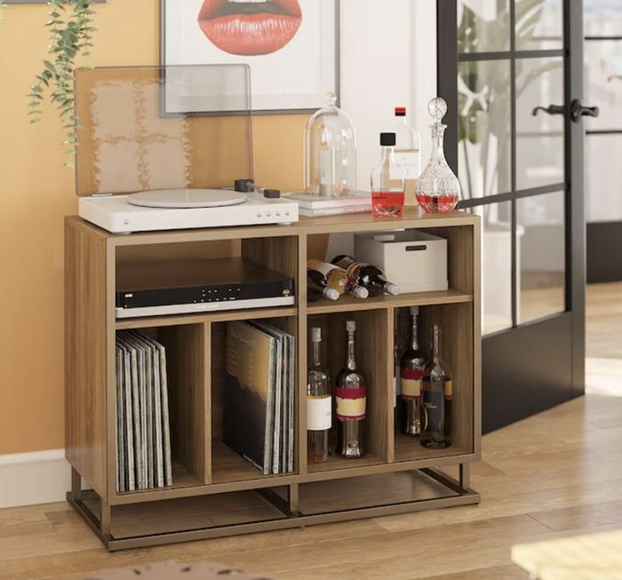 Record player on a stylish wooden cabinet with a raised lid, storing vinyl records, wine, and spirits in a sleek, modern living room arrangement
