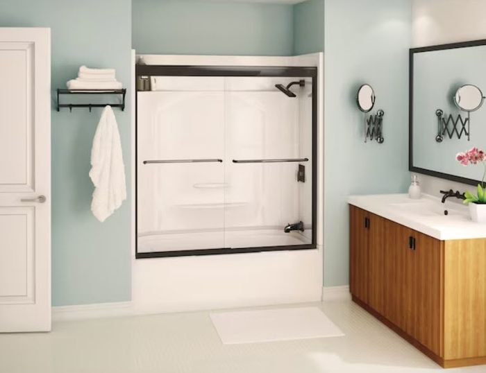 A contemporary bathroom featuring a sleek glass-enclosed shower, neatly folded towels on a towel rack, a stylish vanity with an elegant mirror, a functional sink, and a wooden storage cabinet.