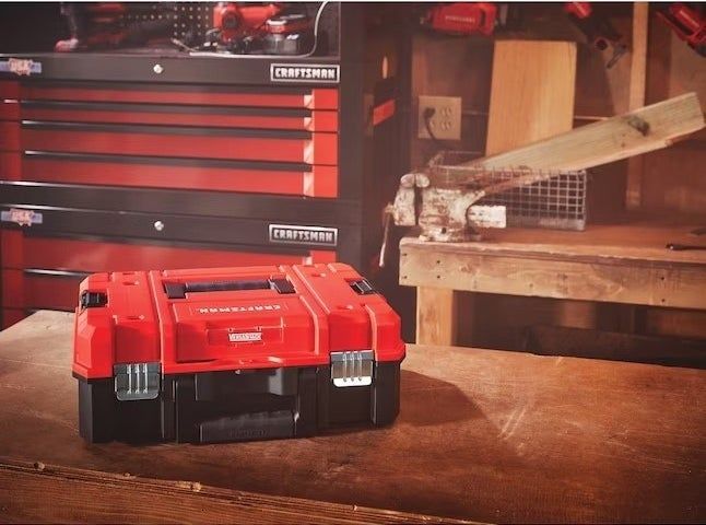A red toolbox sitting in a room with wooden flooring