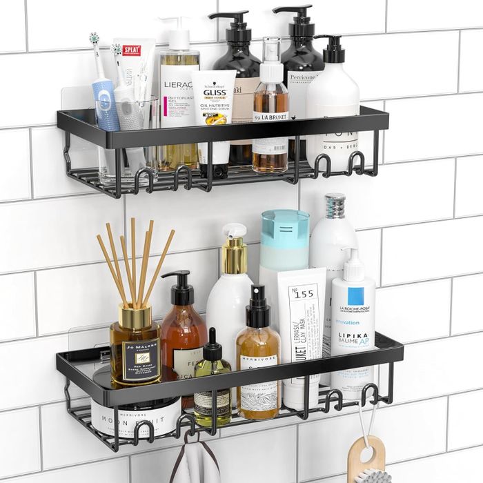 Two dark metal-colored, stick-on shower shelves packed with plenty of products