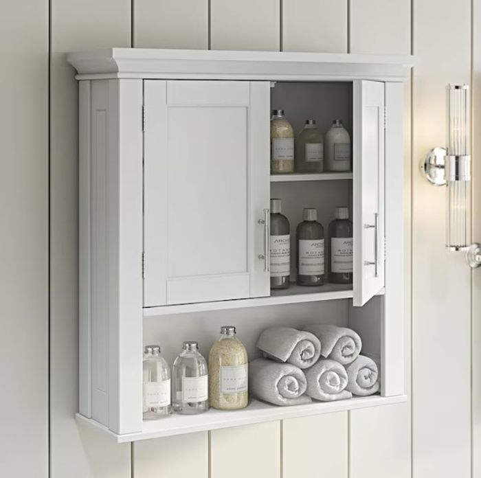A bathroom cabinet mounted on the wall, with towels and toiletries neatly organized on its shelves.