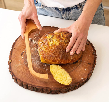 A person cutting bread on a wooden surface using a bread knife.