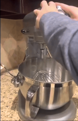A person effortlessly slides a stand mixer across a kitchen counter, making use of appliance sliders.